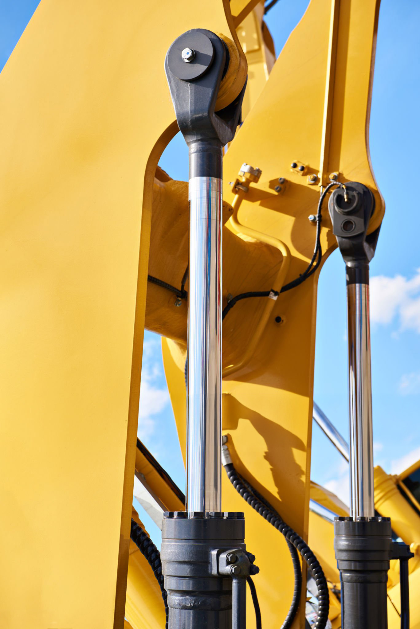 A close up of two hydraulic cylinders on agriculture machinery